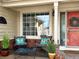 Inviting front porch with seating area, decorative pillows, and a welcoming red front door with wreath at 5090 Golden Valley Trl, Castle Rock, CO 80109
