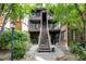 Inviting condo complex featuring brick and wood exterior, lush greenery, and a central staircase leading to upper units at 830 S Vance St # F, Lakewood, CO 80226