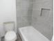 Bathroom showcases gray tiled walls with a shower niche and a white bathtub and toilet at 9887 E Peakview Ave # F06, Englewood, CO 80111