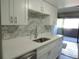 The bright kitchen features white cabinetry, marble backsplash, stainless steel dishwasher and access to the deck at 9887 E Peakview Ave # F06, Englewood, CO 80111