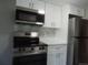 The renovated kitchen features stainless steel microwave, range and refrigerator, complemented by white cabinets at 9887 E Peakview Ave # F06, Englewood, CO 80111