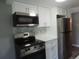 The renovated kitchen features stainless steel appliances including a microwave and range, and white cabinets at 9887 E Peakview Ave # F06, Englewood, CO 80111