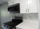 Updated kitchen features microwave and range, with white cabinets and marble backsplash at 9887 E Peakview Ave # F06, Englewood, CO 80111