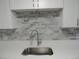Bright kitchen features marble backsplash and stainless steel sink and faucet with white cabinets at 9887 E Peakview Ave # F06, Englewood, CO 80111