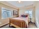 Cozy bedroom features a wooden bed frame, tan walls, tray ceiling, and carpeted floors at 10935 Valleybrook Cir, Highlands Ranch, CO 80130