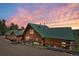Stunning log home with a green metal roof and beautiful sunset views nestled in a serene natural setting at 10268 Christopher Dr, Conifer, CO 80433