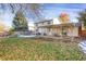 This backyard has a covered patio, a well maintained lawn, mature trees, and a trampoline at 6431 W Arbor Ave, Littleton, CO 80123