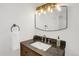 Modern bathroom vanity with a stone countertop, white sink, and decorative light fixture at 6431 W Arbor Ave, Littleton, CO 80123