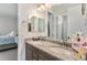 Bright bathroom featuring dual sinks, granite countertops, and a view into the connected bedroom at 5736 Cadara Way, Parker, CO 80134