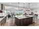 Open kitchen view showcasing the large island, pendant lighting, stainless steel appliances, and hardwood flooring at 5736 Cadara Way, Parker, CO 80134