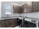 Well-appointed laundry room with gray cabinets, granite countertop, stainless washer and dryer at 5736 Cadara Way, Parker, CO 80134