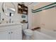 Bright bathroom with white cabinets, tile flooring, tub with shower, and a round mirror at 5090 S Perry Park Rd, Sedalia, CO 80135