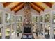 Bright living room with wood ceilings, stone fireplace, chandelier, and wall to wall windows with treed views at 5090 S Perry Park Rd, Sedalia, CO 80135