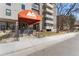 Inviting entrance to Mountain Shadows Condominiums with an orange awning and well-maintained landscaping at 2 Adams St # 608, Denver, CO 80206