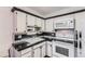 Compact kitchen with classic white cabinets, black countertops, and modern appliances at 735 S Clinton St # 5B, Denver, CO 80247
