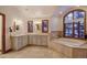 Elegant bathroom featuring dual sinks, a soaking tub with a large window, and neutral tile flooring at 127 Marks Ln, Breckenridge, CO 80424
