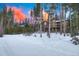 Distant exterior view of multi-story home with deck and wood and stone facade, surrounded by tall pine trees in winter at 127 Marks Ln, Breckenridge, CO 80424