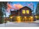 Garage exterior with stone details and wood paneling, with an arched entryway and a backdrop of a stunning sunset at 127 Marks Ln, Breckenridge, CO 80424