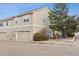 Exterior view of a two-story townhome, featuring a two-car garage and mature trees and landscaping at 9431 Crossland Way, Highlands Ranch, CO 80130