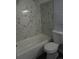 Bathroom featuring bathtub and shower combo and toilet, with modern tile on the walls at 8832 Lipan St, Thornton, CO 80260