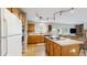 Open kitchen area featuring an island with a cooktop, wood cabinets, and access to the living room at 1089 E 131St Dr, Thornton, CO 80241