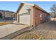 The side exterior view of the property includes a long driveway and a brick and siding facade at 11197 W 64Th Pl, Arvada, CO 80004