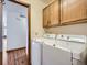 Bright laundry room with washer, dryer and overhead cabinets at 11197 W 64Th Pl, Arvada, CO 80004