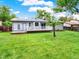 A view of the home's backyard, featuring a well-kept lawn, a small deck, and privacy fence at 6943 Ingalls St, Arvada, CO 80003