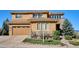 Two-story home featuring a tan stucco and stone facade with an attached two-car garage at 10751 Manorstone Dr, Highlands Ranch, CO 80126