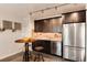 Charming kitchenette featuring stainless steel appliances, dark cabinets, and a unique bistro table at 10751 Manorstone Dr, Highlands Ranch, CO 80126