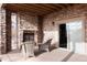 Covered patio featuring a stone fireplace, two chairs, and a sliding glass door at 10751 Manorstone Dr, Highlands Ranch, CO 80126