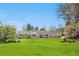 Expansive backyard with lush green grass, a cozy porch, and mature trees at 21 Fairway Ln, Littleton, CO 80123