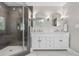 Bright bathroom featuring double vanity, elegant mirrors, and a glass-enclosed shower with tile surround at 21 Fairway Ln, Littleton, CO 80123