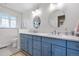 Bright bathroom with blue cabinets, double sinks, framed mirrors, and lots of natural light at 21 Fairway Ln, Littleton, CO 80123
