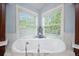 Bright bathroom features a standalone soaking tub with chrome fixtures sitting beneath two large windows at 980 E Tufts Ave, Cherry Hills Village, CO 80113