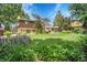 Backyard with large lawn, flowers, trees and patio area with furniture at 11496 E Wesley Ave, Aurora, CO 80014
