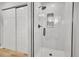 Modern shower with glass enclosure, tiled walls, and convenient built-in shelving for storage at 11496 E Wesley Ave, Aurora, CO 80014