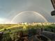 Scenic backyard view with double rainbow, houses in the distance, outdoor seating and fire pit at 10580 Greycliffe Dr, Highlands Ranch, CO 80126