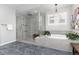 Elegant bathroom features a glass-enclosed shower, a soaking tub, and stylish herringbone tile flooring at 10580 Greycliffe Dr, Highlands Ranch, CO 80126