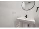 Minimalist bathroom features a pedestal sink, round mirror, and sleek black fixtures at 10163 W 38Th Ave, Wheat Ridge, CO 80033