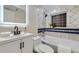 This updated bathroom features a modern vanity, backlit mirror, and tiled tub with shower at 1880 E 81St Pl, Denver, CO 80229