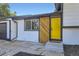 Stylish home featuring a striking yellow door and a uniquely designed wood accent wall at 1880 E 81St Pl, Denver, CO 80229