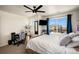 Bedroom with a white comforter, dark curtains, ceiling fan, and a gray gaming chair in the corner at 760 N Allium St, Watkins, CO 80137