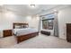 Bright bedroom with a large window, tray ceiling, and a comfortable upholstered bench at 11511 E 118Th Ave, Commerce City, CO 80640