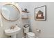 Stylish powder room featuring a round mirror, pedestal sink, and rustic decor at 527 Antelope E Dr, Bennett, CO 80102