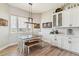 Cozy dining area with a charming chandelier, white chairs and bench, and views from the windows at 527 Antelope E Dr, Bennett, CO 80102