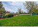 Large backyard with mature trees, manicured lawn, and partial view of home's exterior, creating a private outdoor space at 11310 W Center Ave, Lakewood, CO 80226