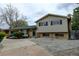 Charming home featuring an attached two-car garage, mature trees, and brick and vinyl siding at 11310 W Center Ave, Lakewood, CO 80226