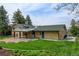 Back exterior view featuring brick, patio, and green grass with mature landscaping that enhances this property's curb appeal at 11310 W Center Ave, Lakewood, CO 80226