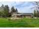 View of the home's rear exterior from the yard, featuring a brick facade and covered patio, offering an inviting outdoor space at 11310 W Center Ave, Lakewood, CO 80226